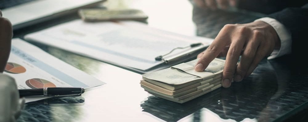 man sliding stack of cash on desk
